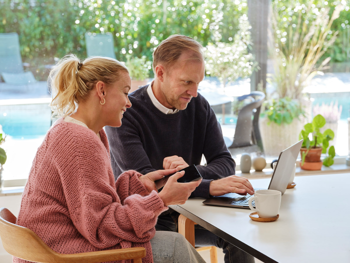 man och kvinna i ett hus sitter vid ett bord framför en dator